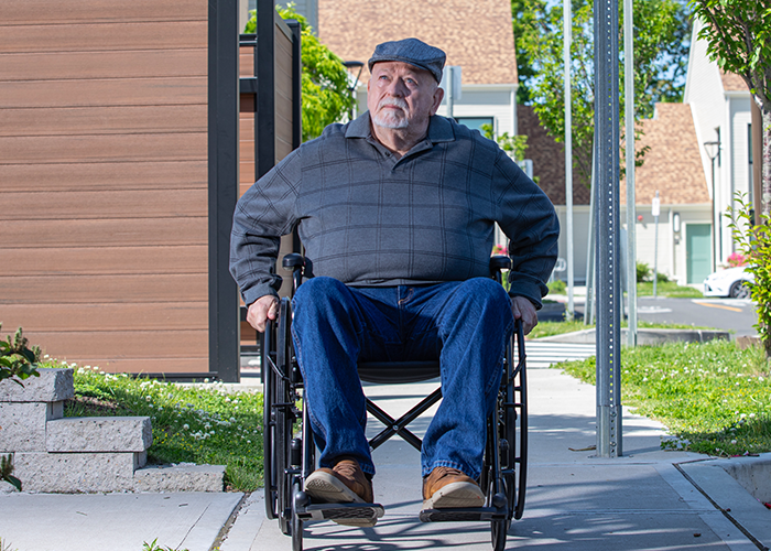 Man in a wheelchair rolling down the street.